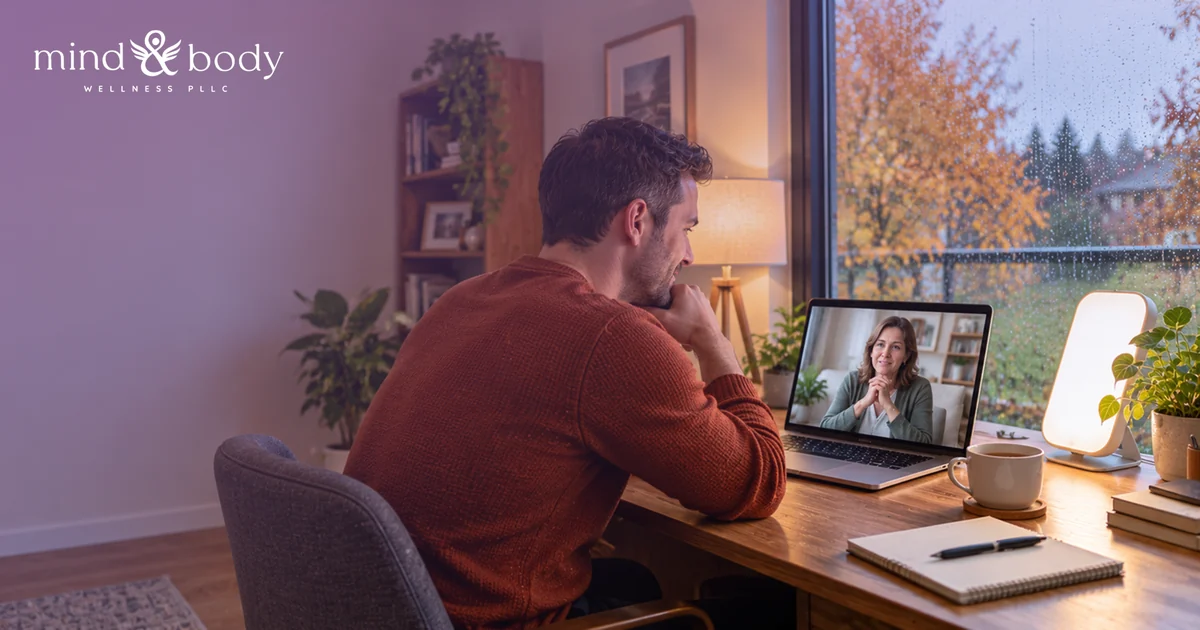Man on a video call with a provider during a telehealth visit on a rainy autumn day, with a light therapy lamp nearby